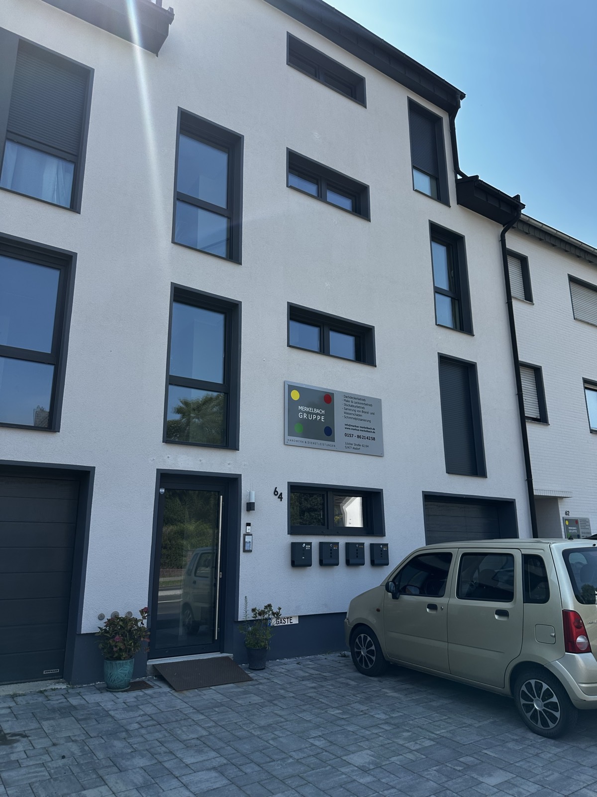 Straßenansicht der Fassade mit anthrazitfarbenen Aluminium-Fenstern und Glas-Eingangstür