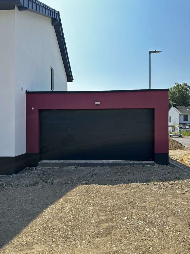 Bordeauxrote Garage mit anthrazitfarbenem Sektionaltor