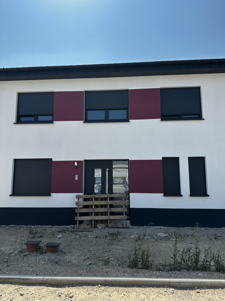 Vorderfassade mit Glas-Eingangstür und anthrazitfarbenen Rollläden